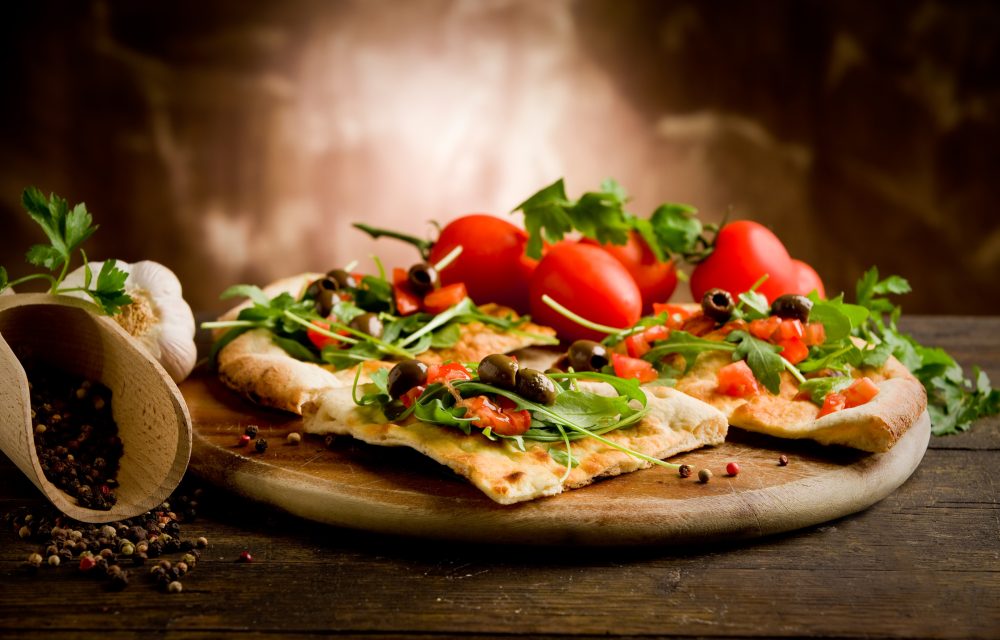 photo of delicious vegetarian pizza with arugula on wooden table