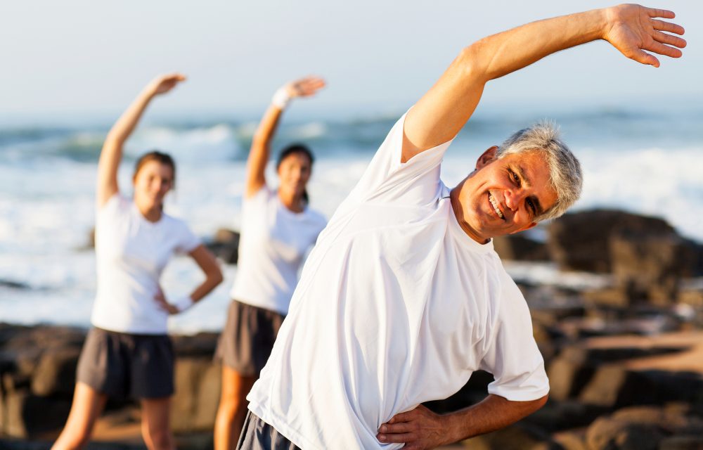 happy mid age man exercising at the beach with his family